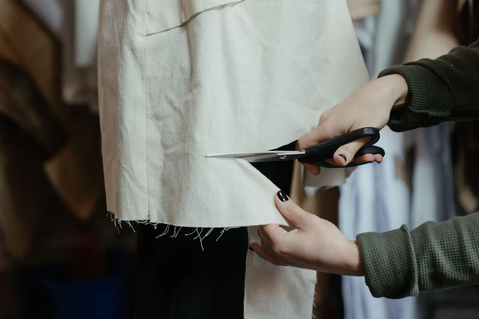 Hands cutting fabric with scissors in a workshop, showcasing the craft of tailoring and fashion design. Putting a real process behind circular fashion design