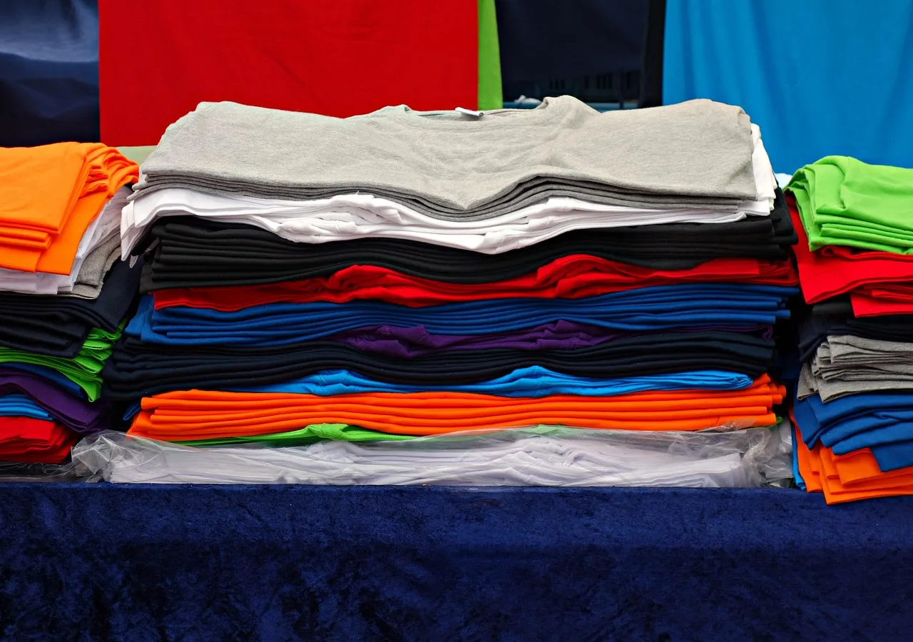 t-shirt, tee, clothing, garment, shirt, fashion, unisex, woman, man, top, casual, pile, pile of t-shirts, market, stall, market stall, t-shirt, t-shirt, t-shirt, t-shirt, t-shirt, shirt, shirt, shirt. Textile EPR rules California New York: status and design