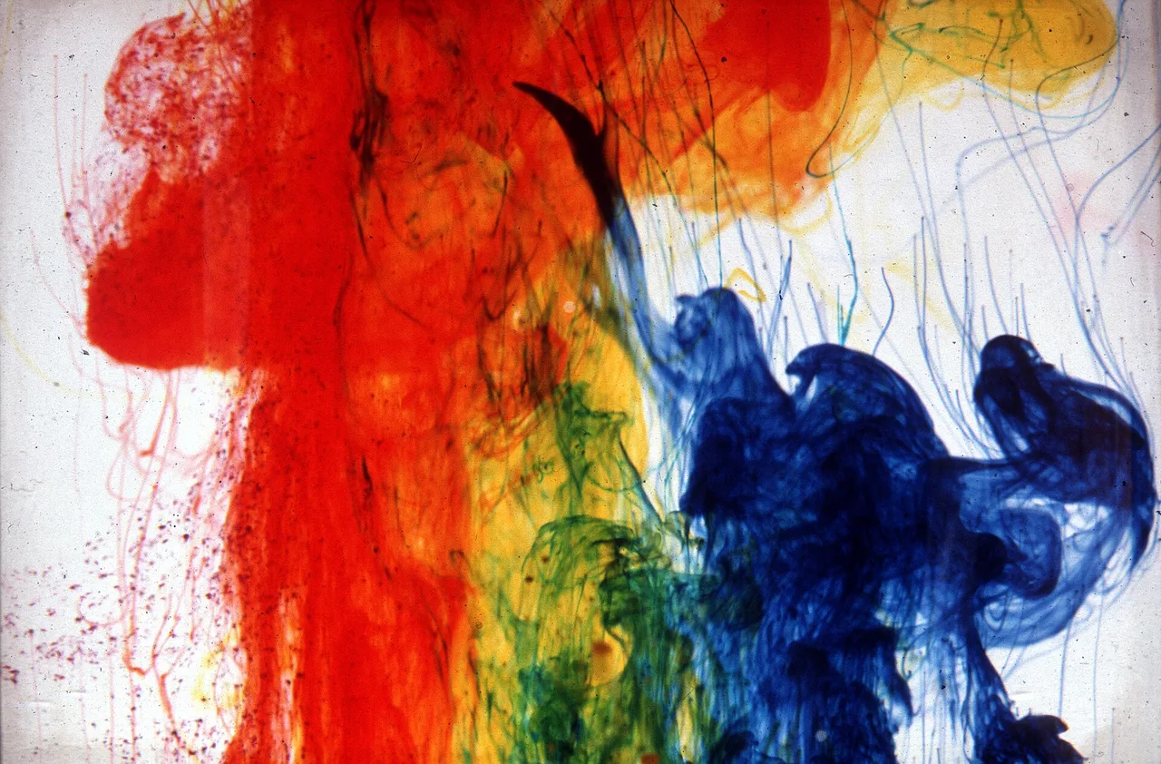Red, yellow, green, and blue textile dye dispersing through water